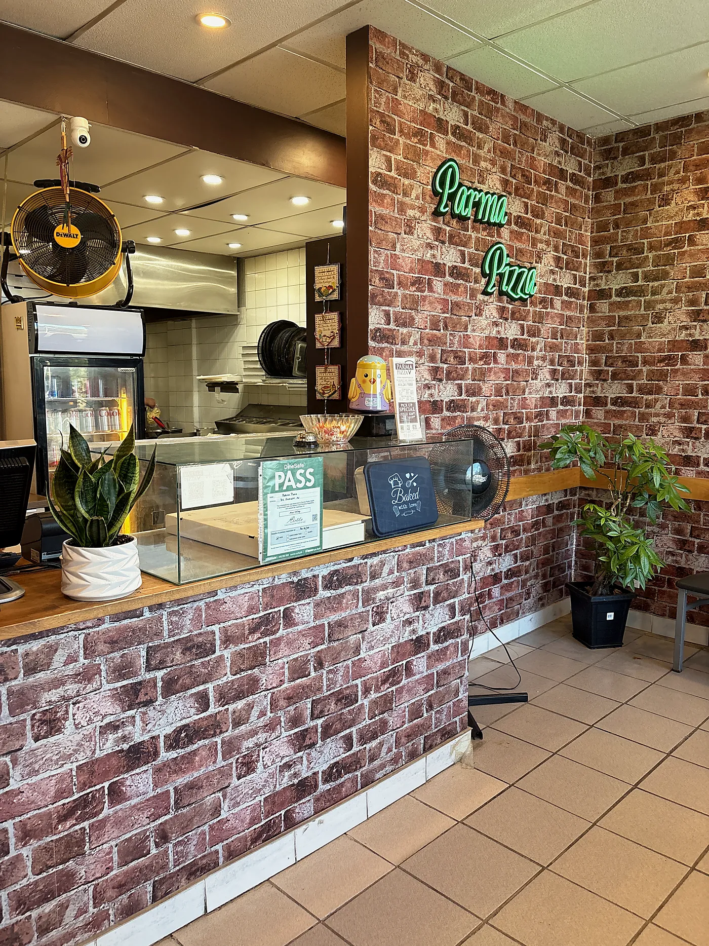 The counter and neon Parma Pizza sign inside the shop